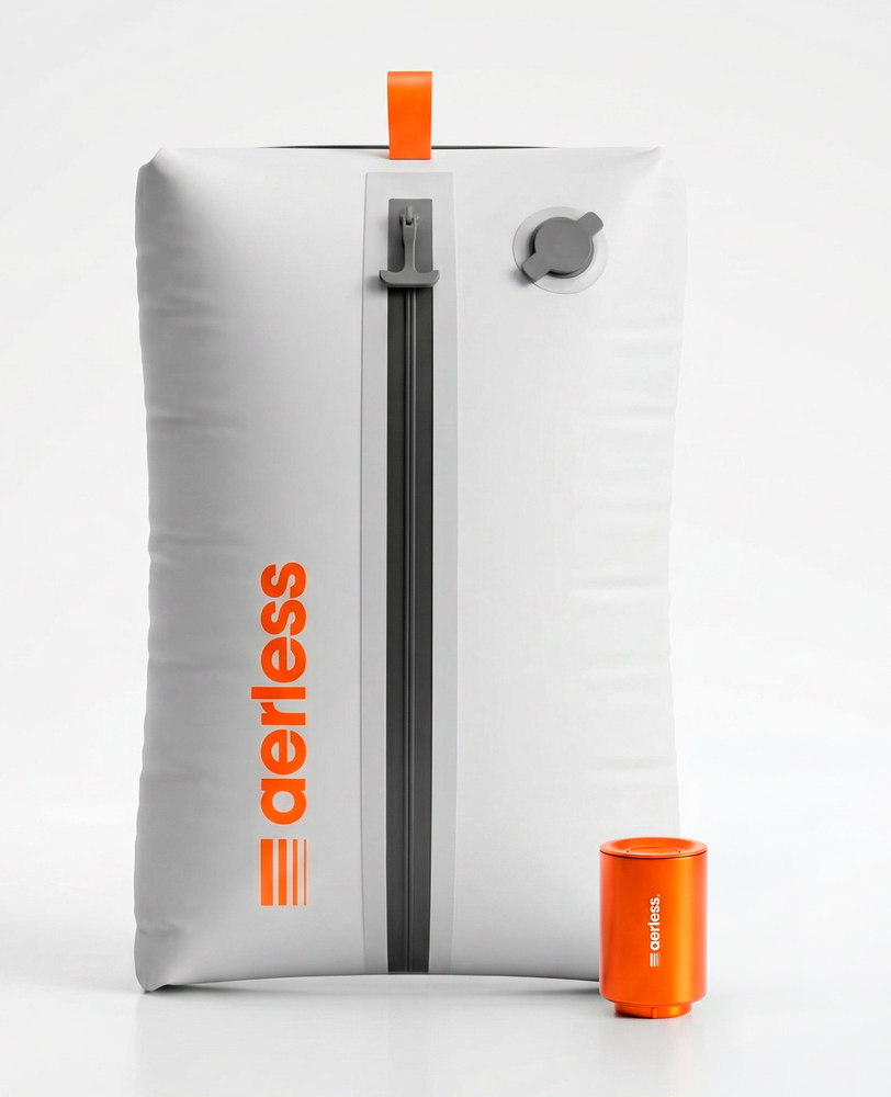 The Aerless kit: a white compressed bag with a grey zip spine down the centre and a valve port at the top, standing beside its small orange rechargeable pump